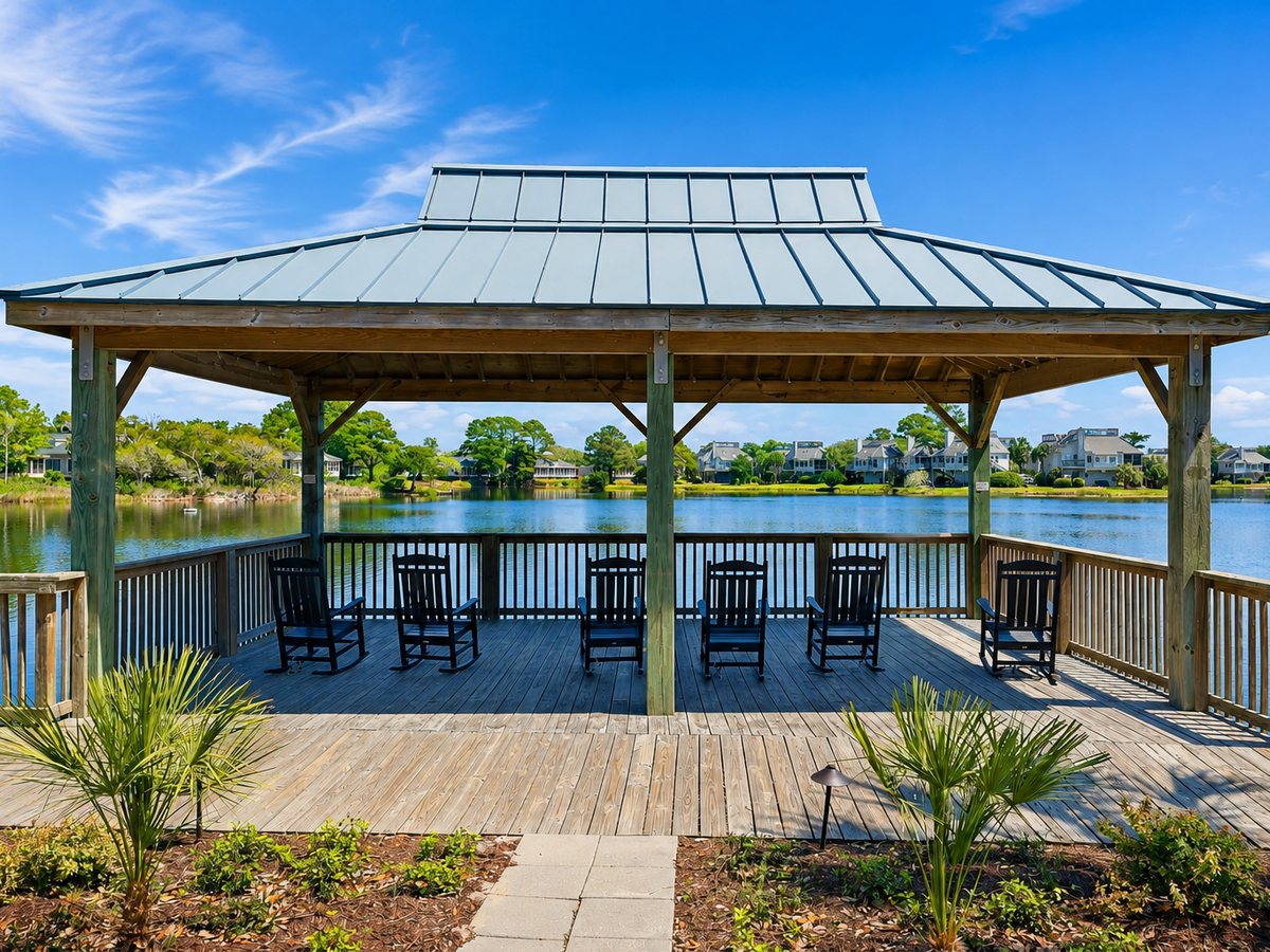 A covered gazebo with rocking chairs looking out over a community lake