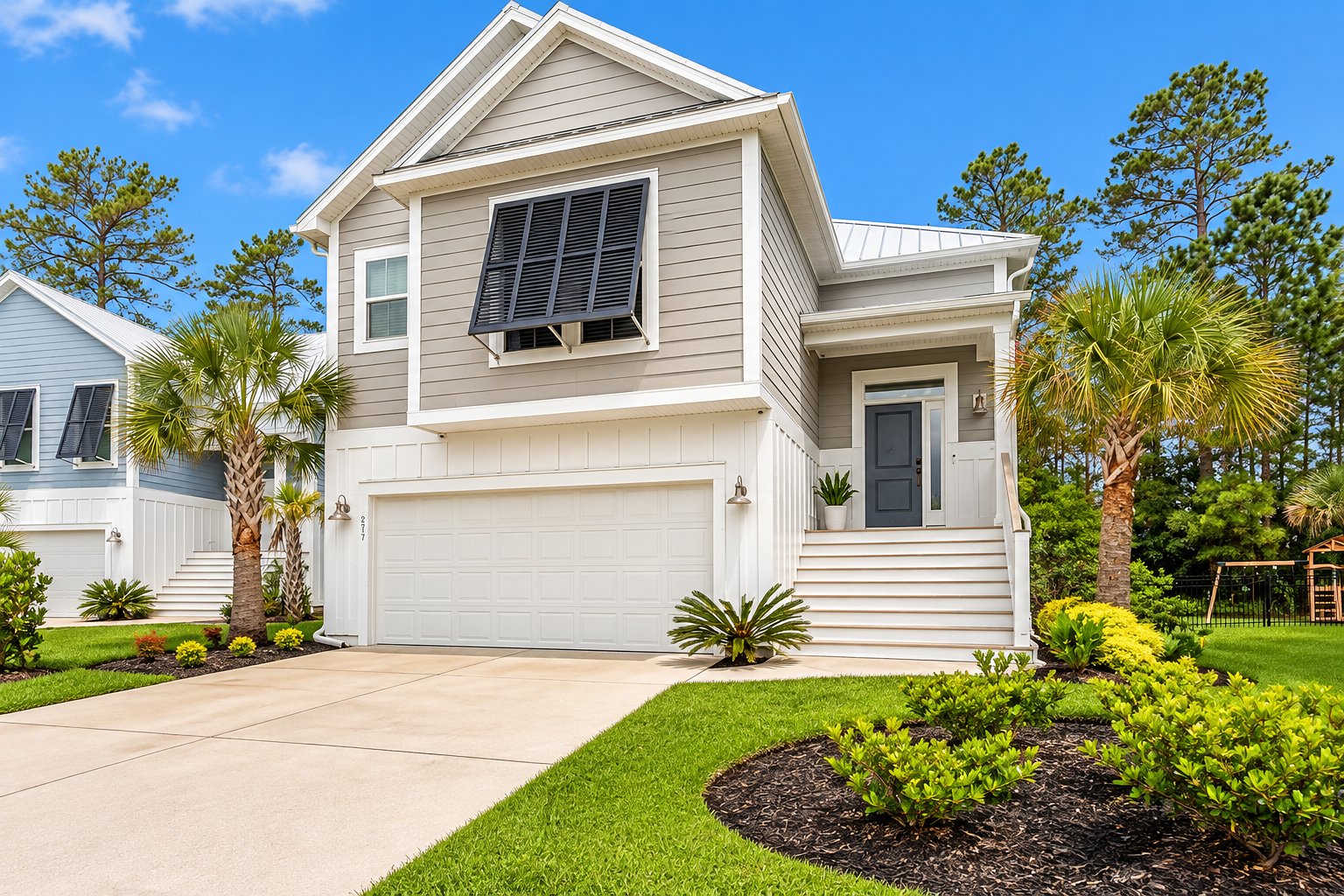 The front of a raised coastal home with palms and a two-car garage
